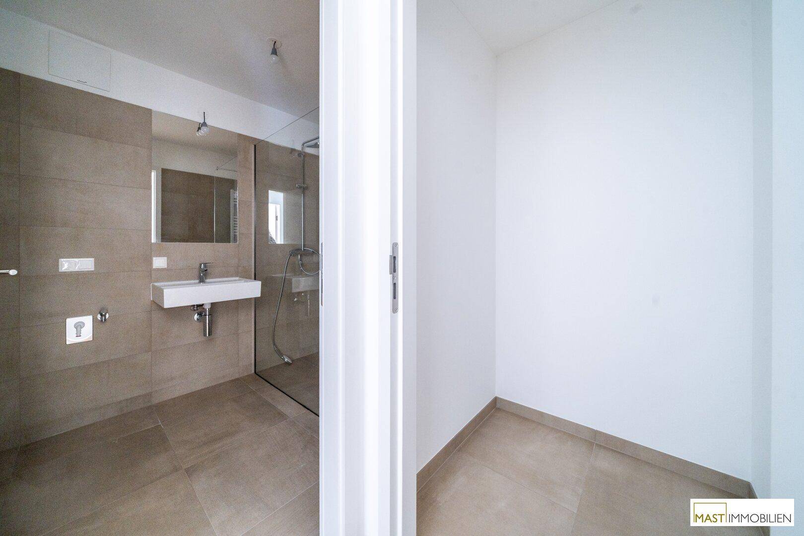 Modernes Badezimmer mit begehbarer Dusche und eleganten Fliesen, teilweise sichtbar.