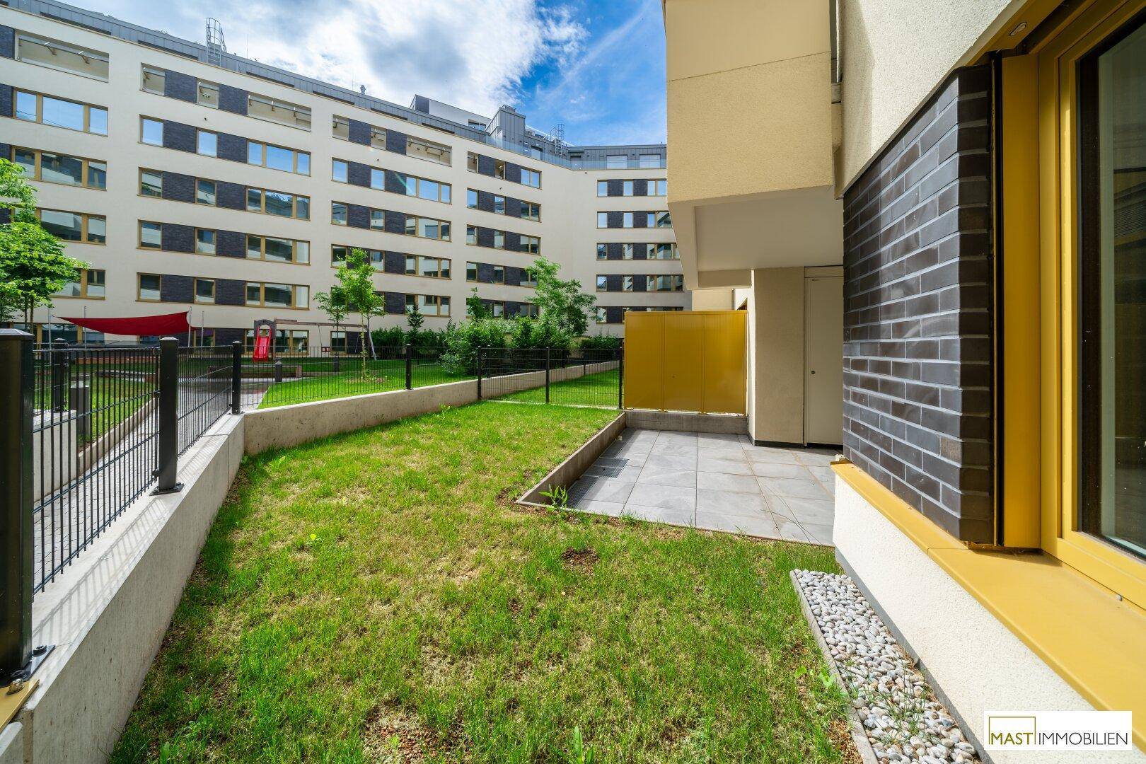 Gepflegter Rasenbereich mit angrenzender Terrasse und Blick auf die umliegenden Wohngebäude.