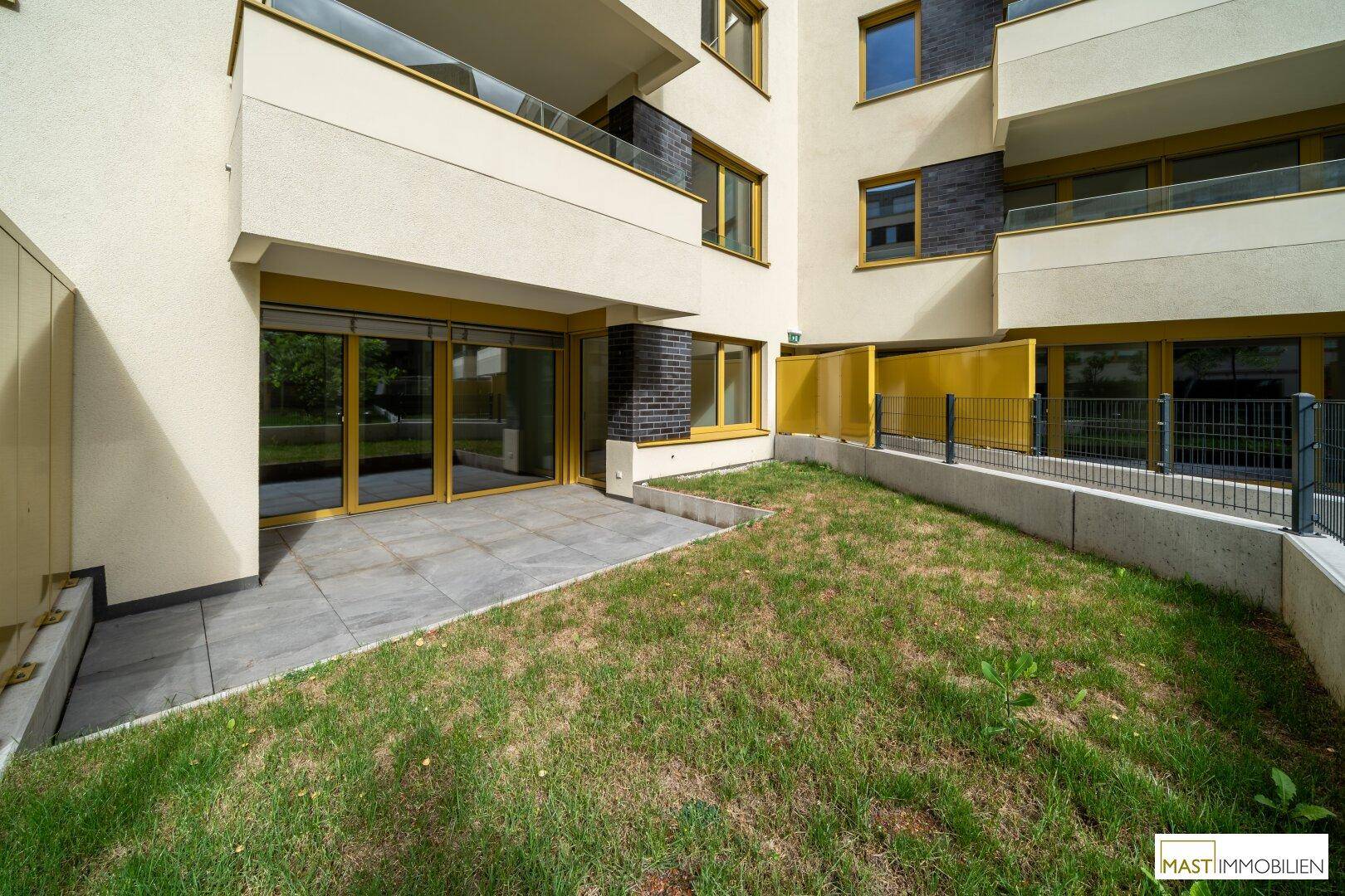 Außenansicht des modernen Wohngebäudes mit privaten Gärten und Terrassen im Erdgeschoss.