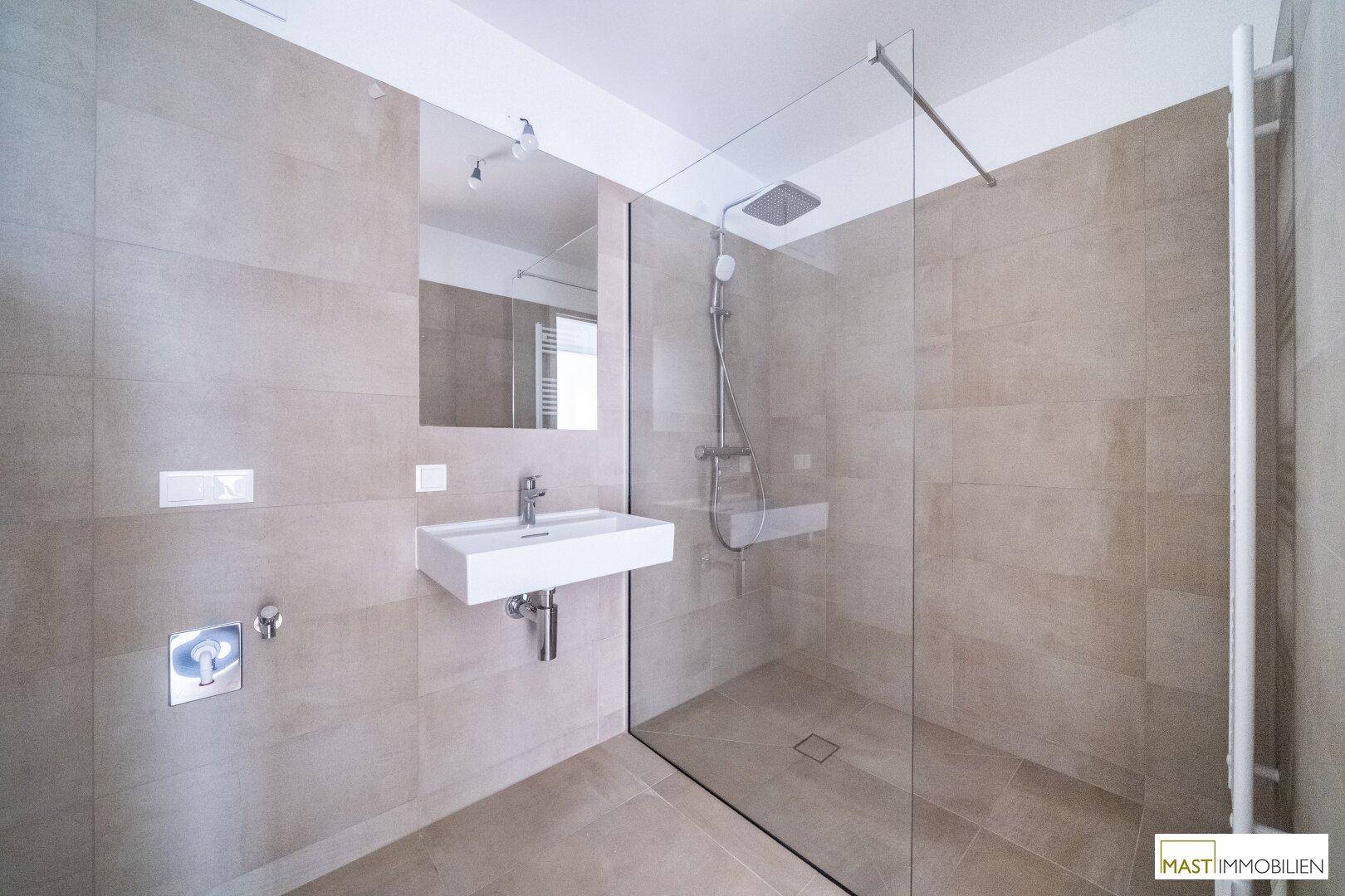 Elegantes Badezimmer mit großer begehbarer Dusche, Regendusche und modernem Waschtisch.