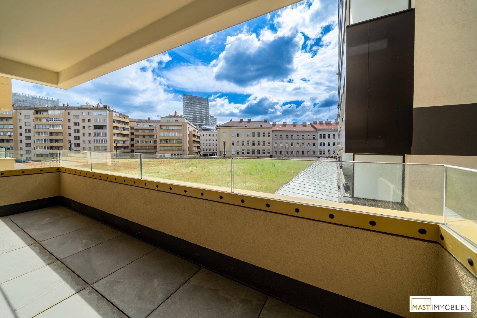 Großer Balkon mit Blick auf die Stadt und eine begrünte Fläche, ideal zum Entspannen.