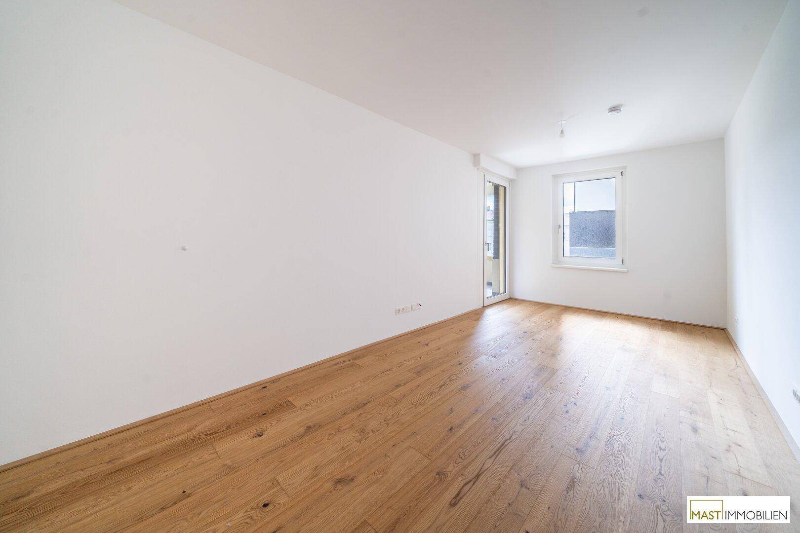 Helles Schlafzimmer mit Holzparkett und einem Fenster, bietet eine ruhige Atmosphäre.