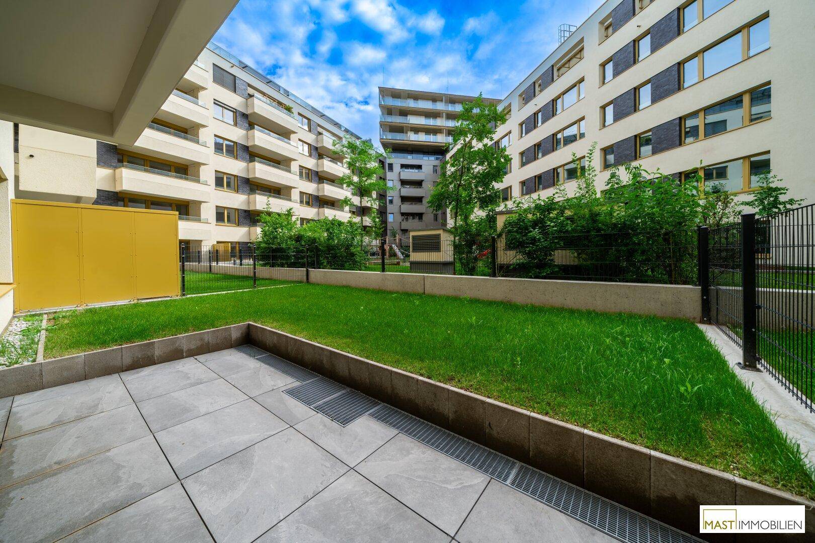 Gepflegter Innenhof mit Rasenflächen und Terrassen, umgeben von modernen Wohngebäuden.