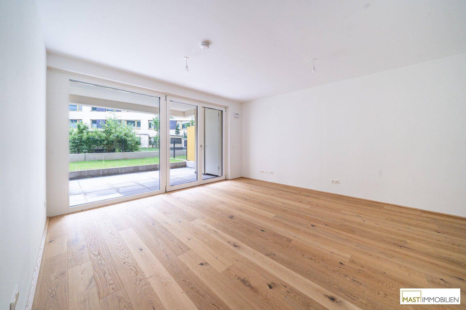 Heller Wohnraum mit Eichenparkettboden und großen Schiebetüren zur Terrasse und zum Garten.