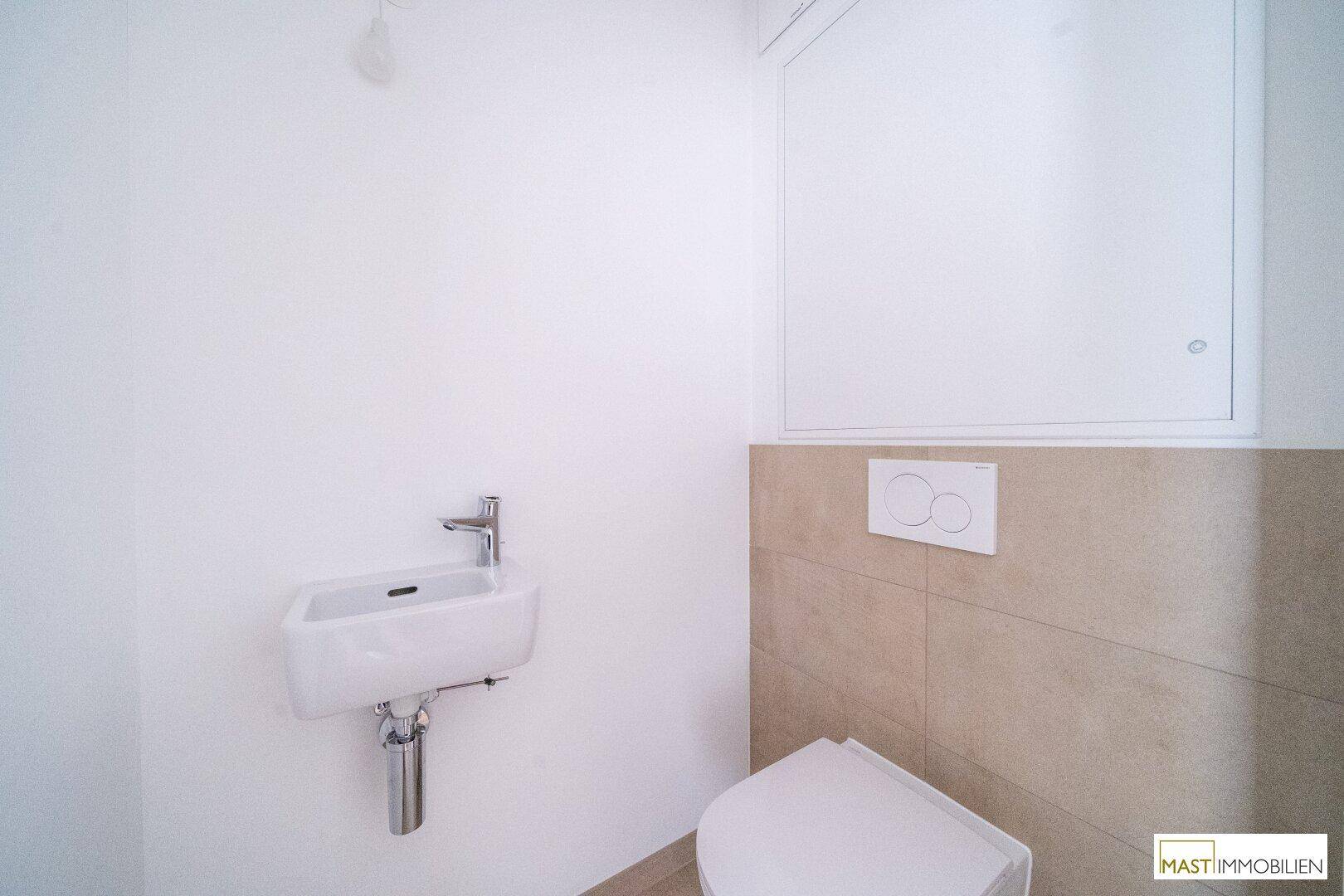 Separates Gäste-WC mit kleinem Waschbecken und Wand-WC, in modernem Design.