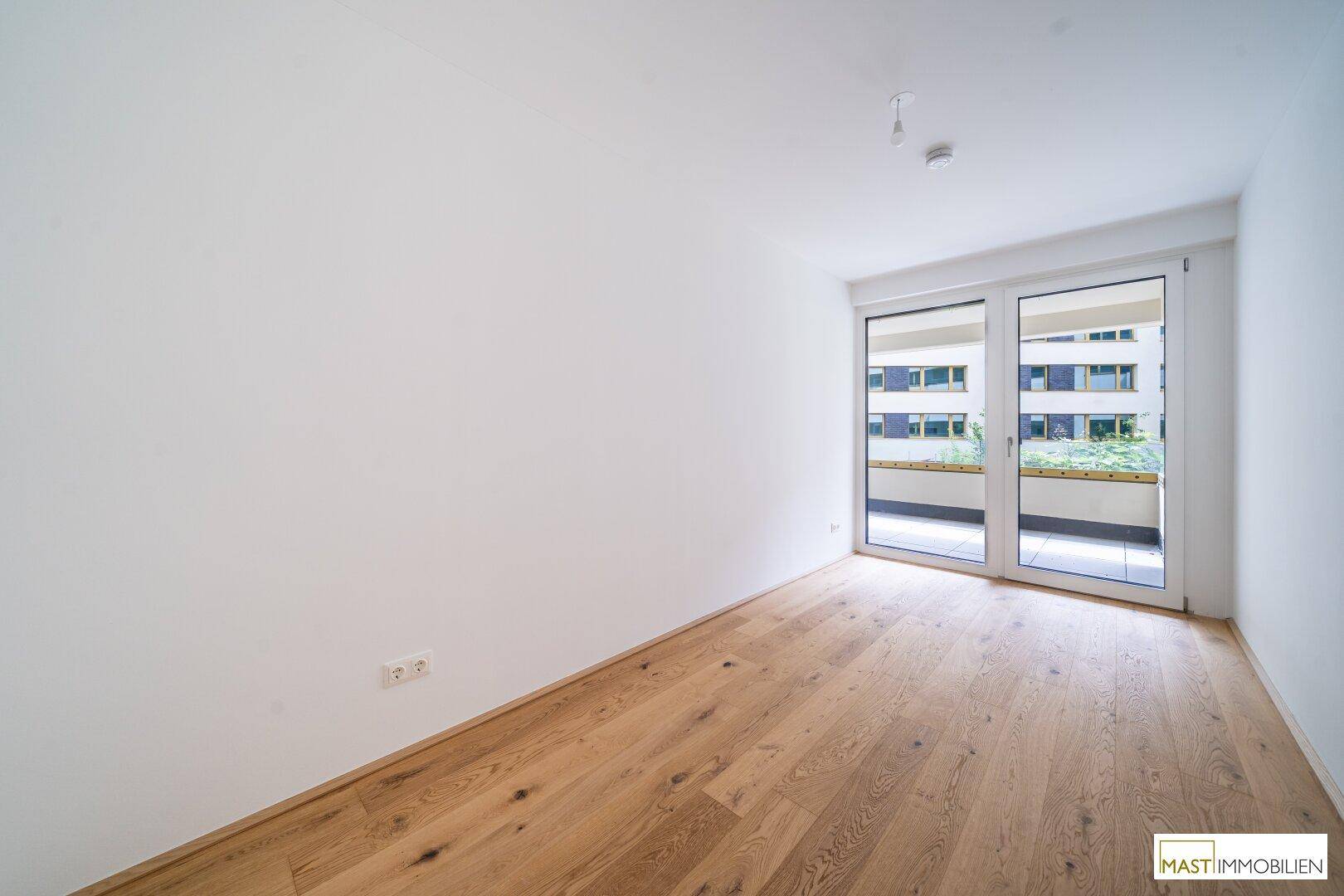 Gemütliches Schlafzimmer mit Holzboden und Balkonzugang, ideal für entspannte Stunden.