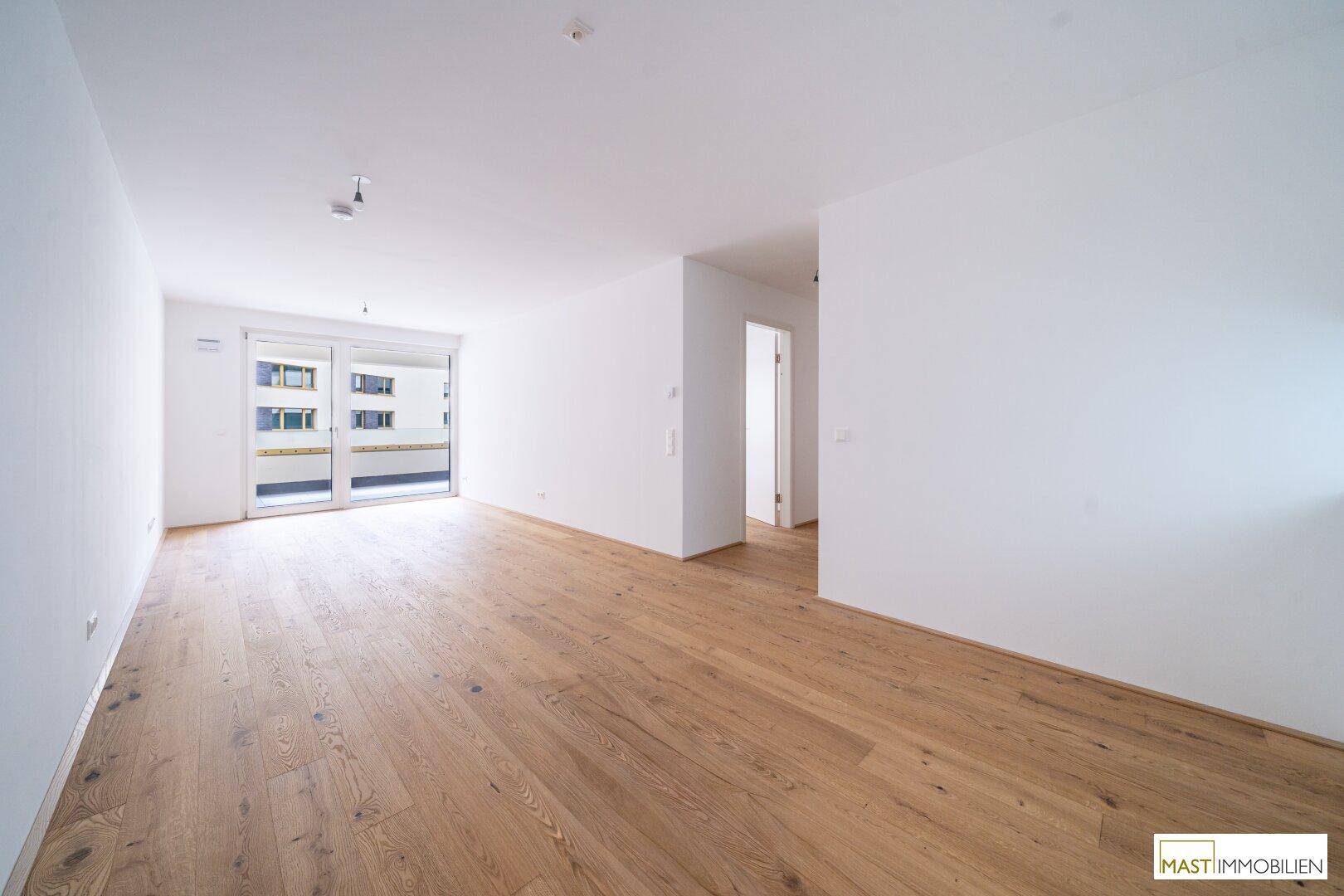 Heller, unmöblierter Raum mit Holzparkett und Zugang zu einem Außenbereich.