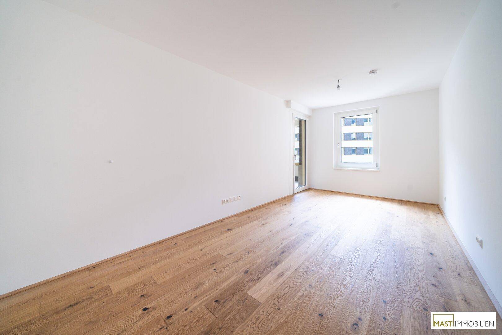 Heller Raum mit Parkettboden und großem Fenster, bietet viel Tageslicht und eine angenehme Atmosphäre.
