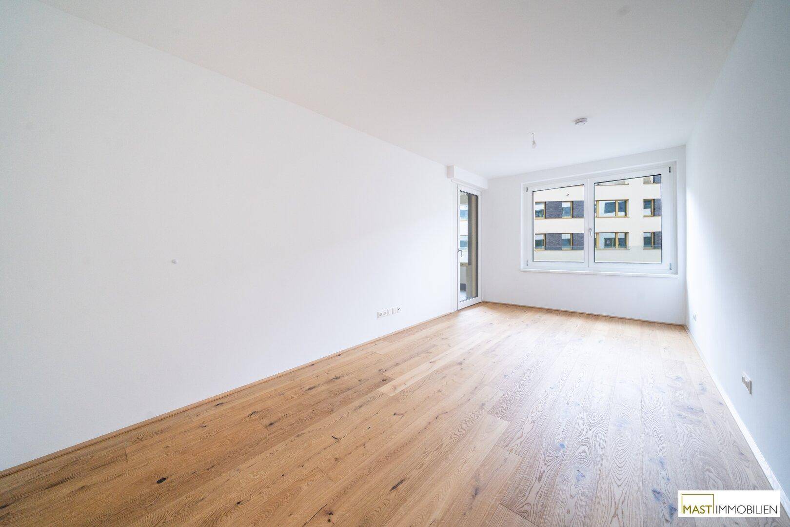 Heller, leerer Raum mit Holzboden und großen Fenstern, bereit zur individuellen Gestaltung.