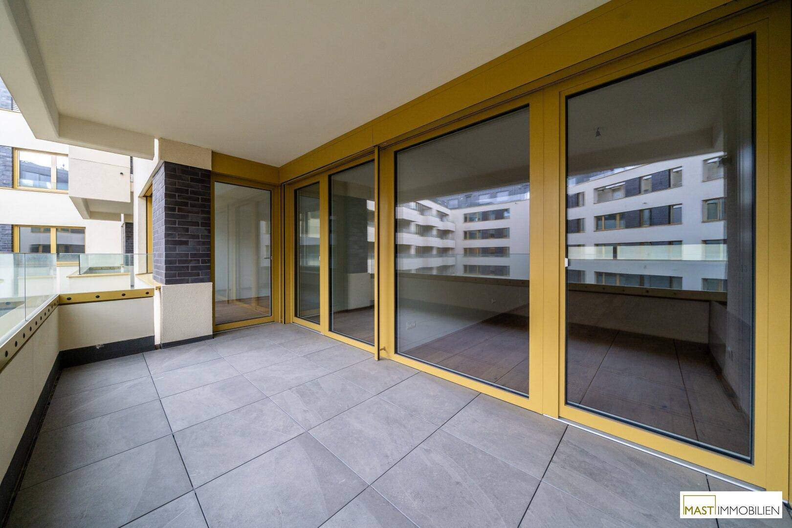Geräumiger Balkon mit Fliesenboden und Blick auf die umliegenden Gebäude, ideal zum Entspannen.