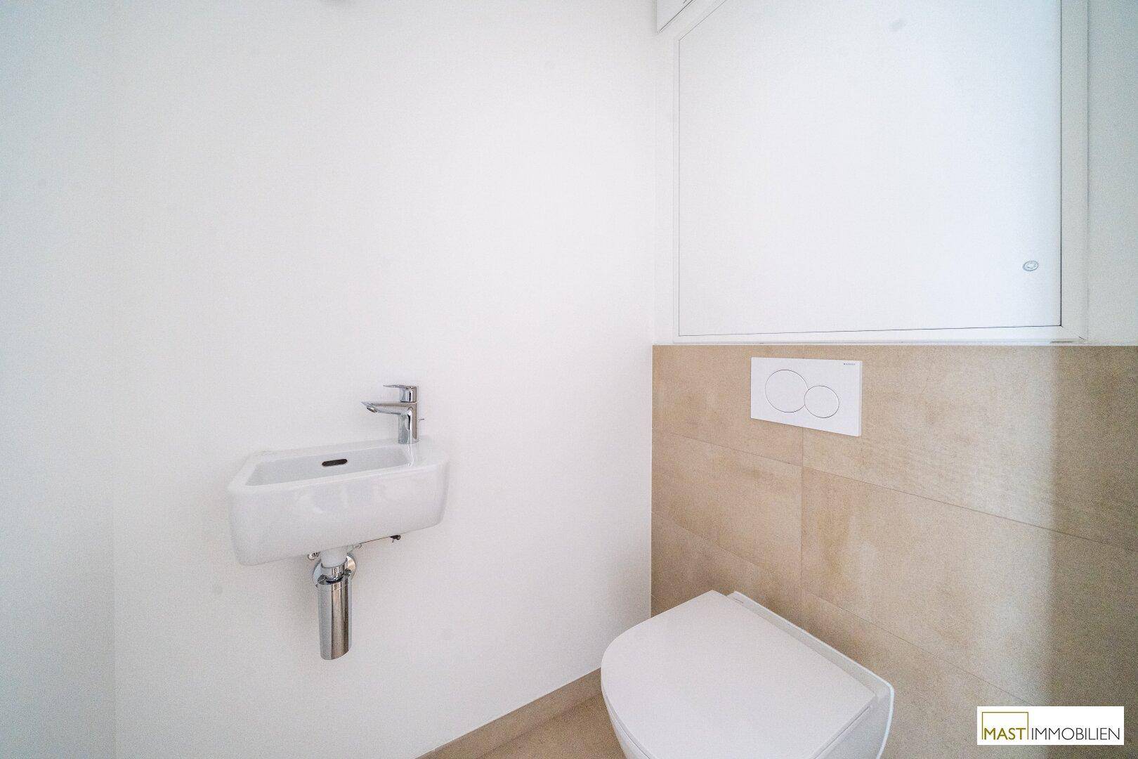 Modernes Gäste-WC mit wandhängendem WC und kleinem Waschbecken, in hellen Fliesen gehalten.