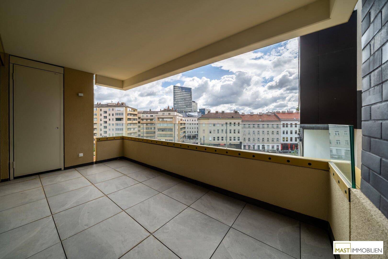Geräumiger Balkon mit Fliesenboden und weitem Blick über die Stadt.