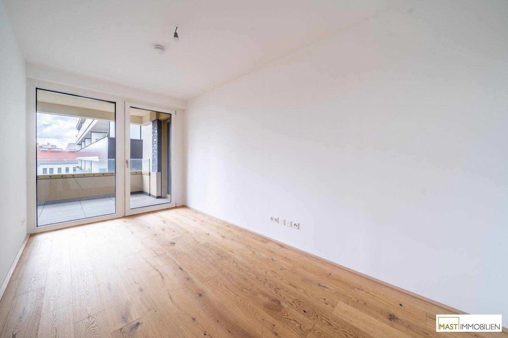 Helles Schlafzimmer mit Holzboden und direktem Zugang zu einem Balkon mit Stadtblick.