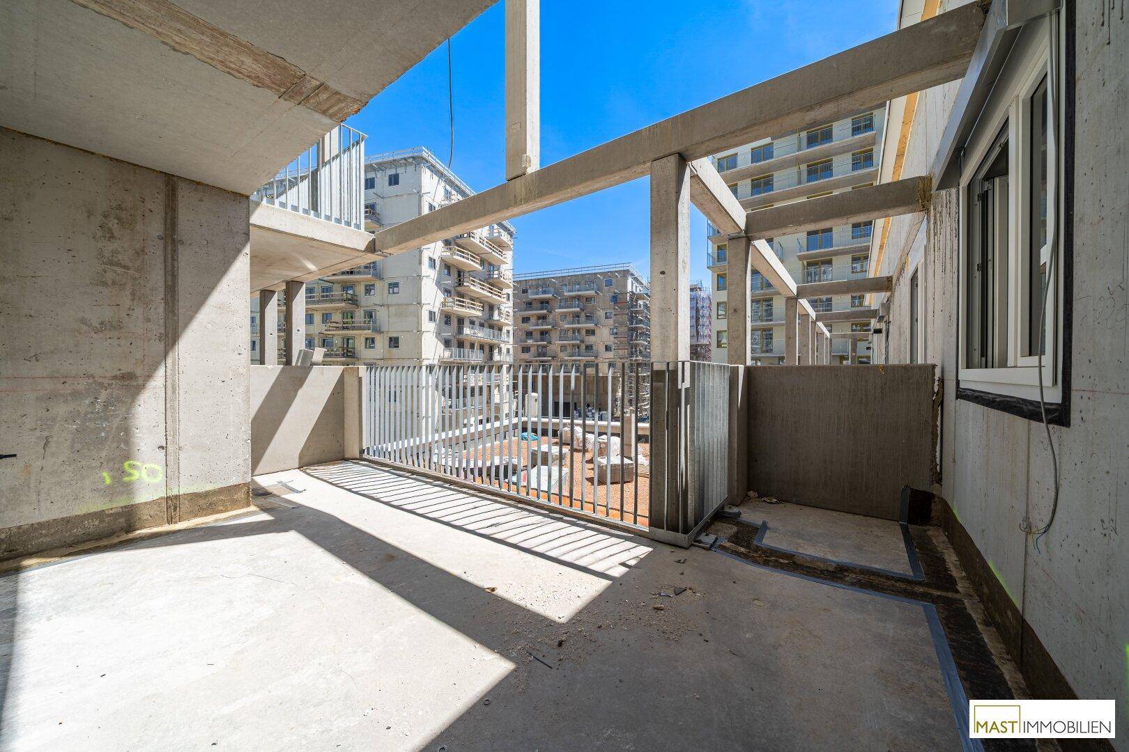 Unfertiger Betonbalkon eines Neubaus mit Blick auf weitere Gebäude in der Stadt.