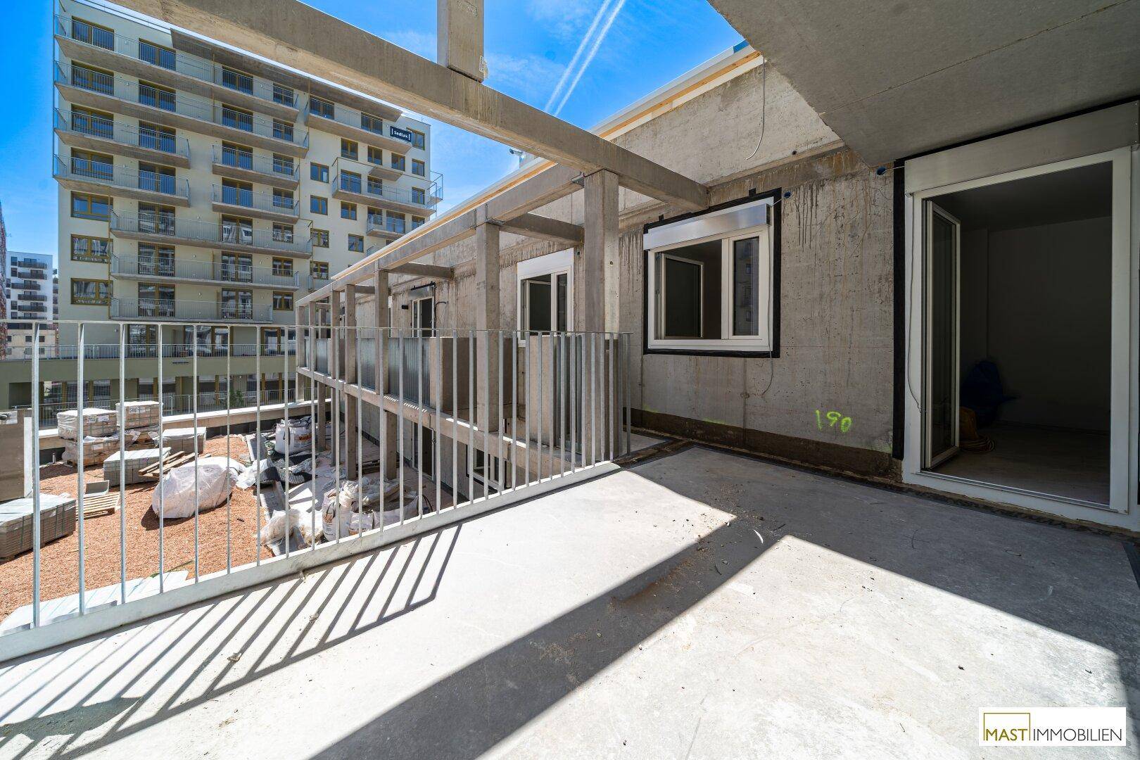 Geräumiger Betonbalkon im Rohbau mit viel Tageslicht und Aussicht auf die Umgebung.