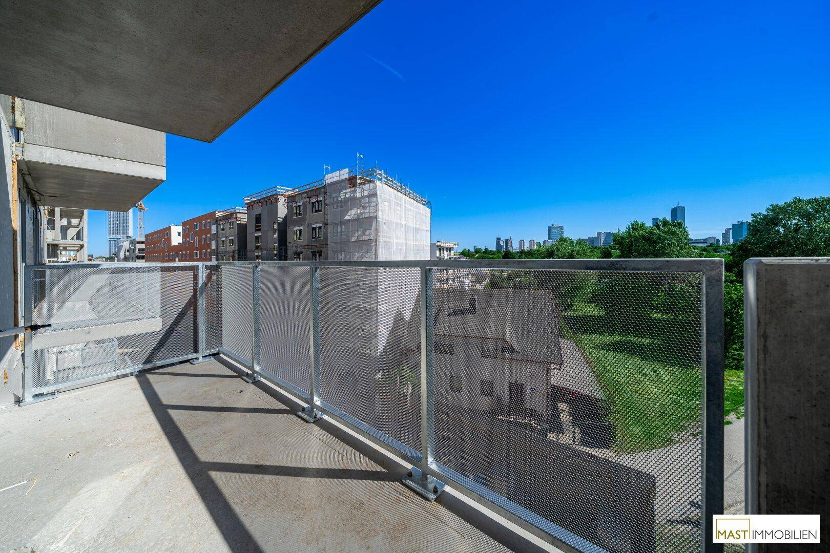 Balkon eines Neubaus mit Blick auf umliegende Gebäude und die Stadtlandschaft.