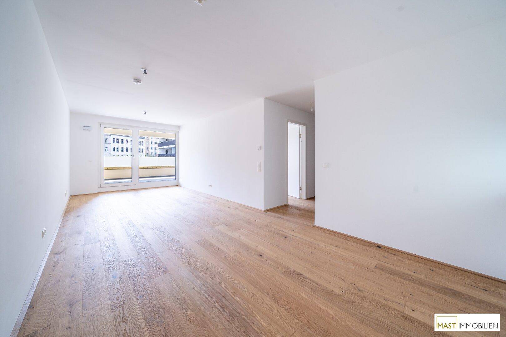 Heller Wohnraum mit Parkettboden und großzügigem Zugang zu einem sonnigen Balkon.