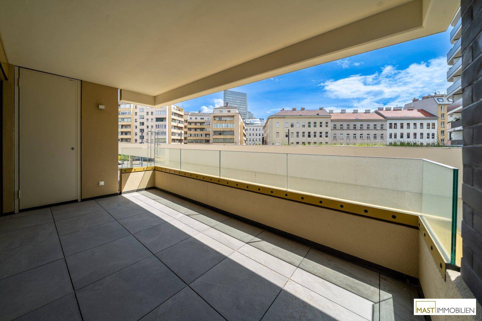 Überdachte Loggia mit Fliesenboden und weitem Blick über die städtische Umgebung.