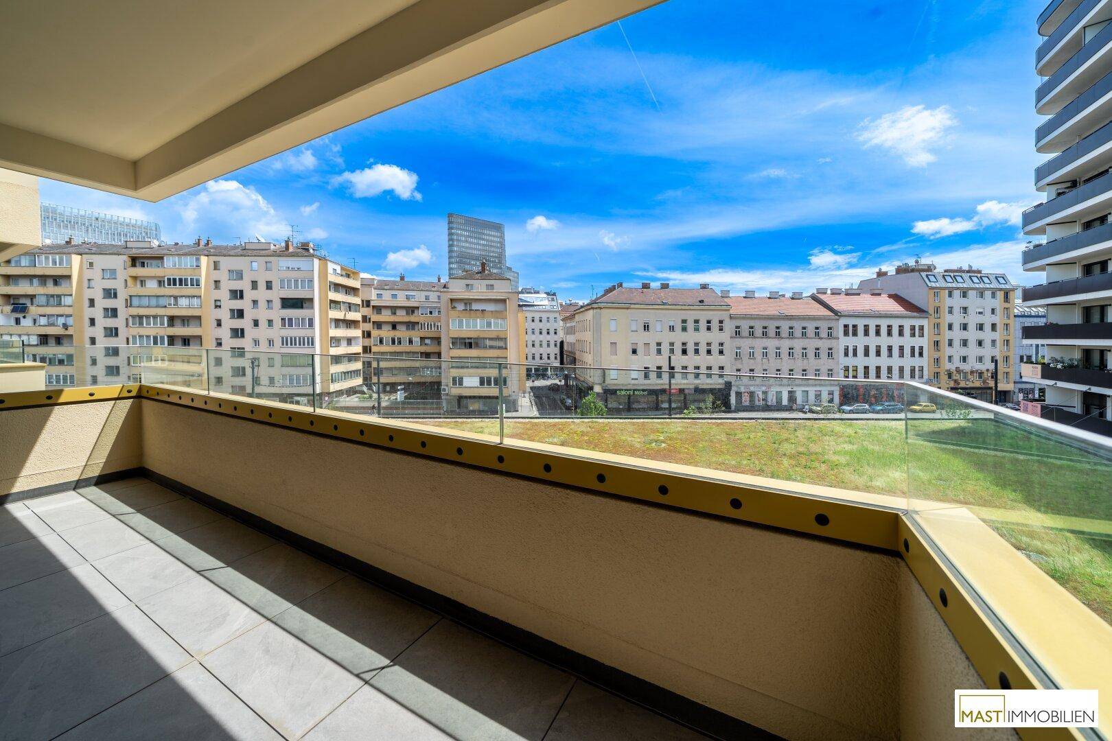 Geräumiger Balkon mit Fliesenboden und Glasgeländer bietet einen weiten Stadtblick.