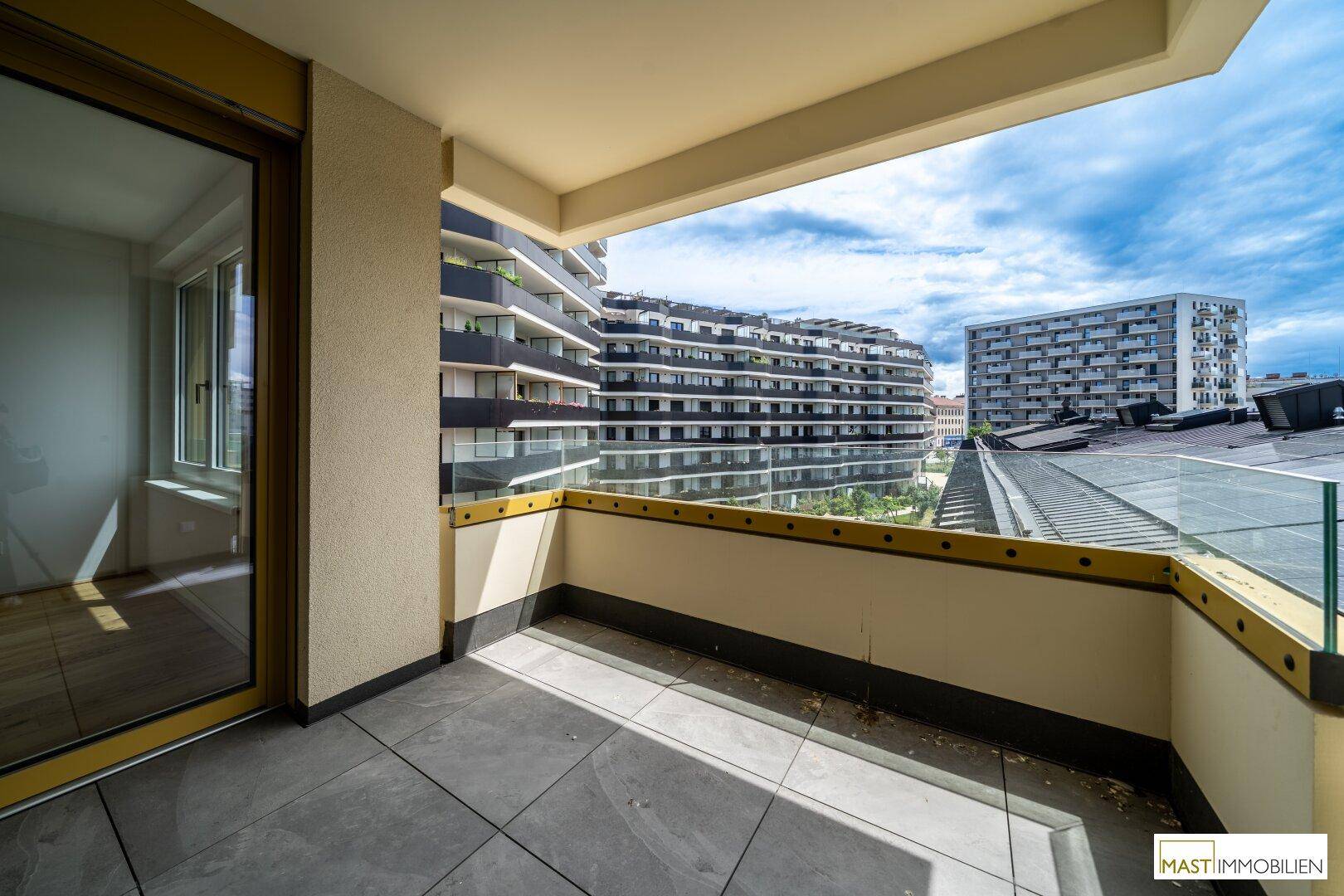 Geräumiger Balkon mit Fliesenboden und weitem Blick auf die umliegende moderne Architektur.