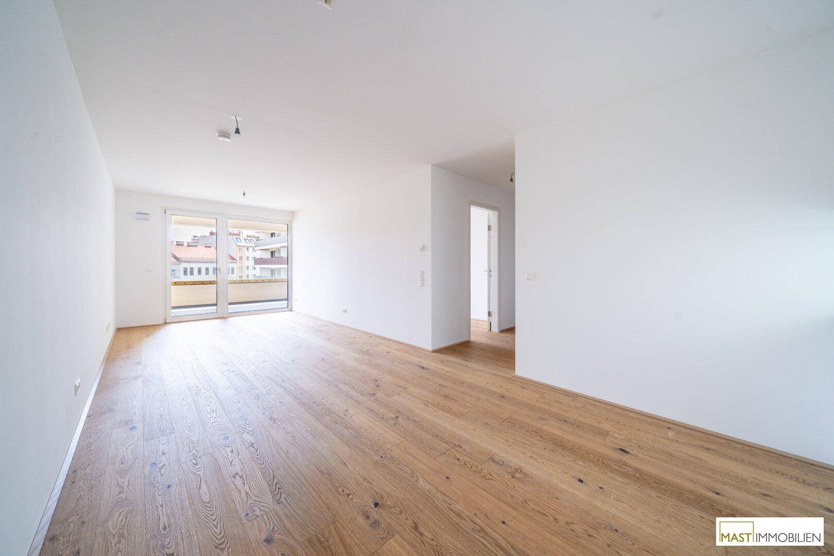 Heller Wohnbereich mit Eichenparkett und Zugang zu einem Balkon, der eine offene Atmosphäre schafft.