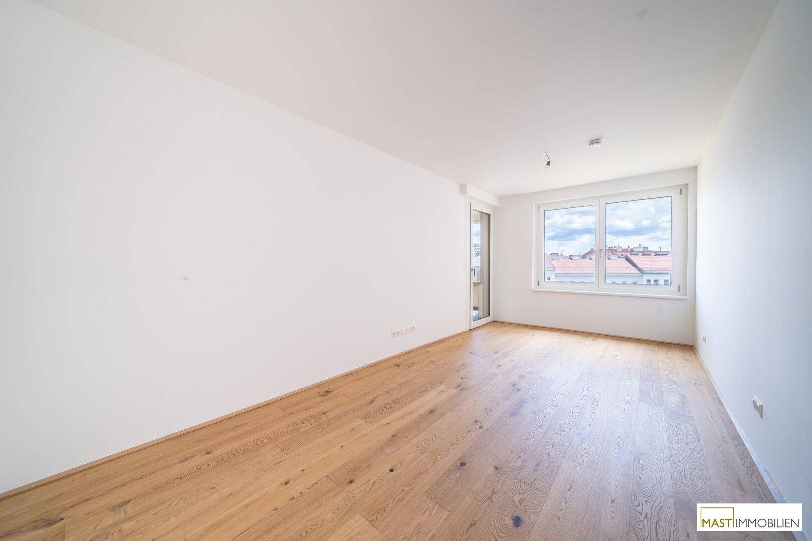 Helles, leeres Zimmer mit Parkettboden und großem Fenster, bereit zur individuellen Gestaltung.