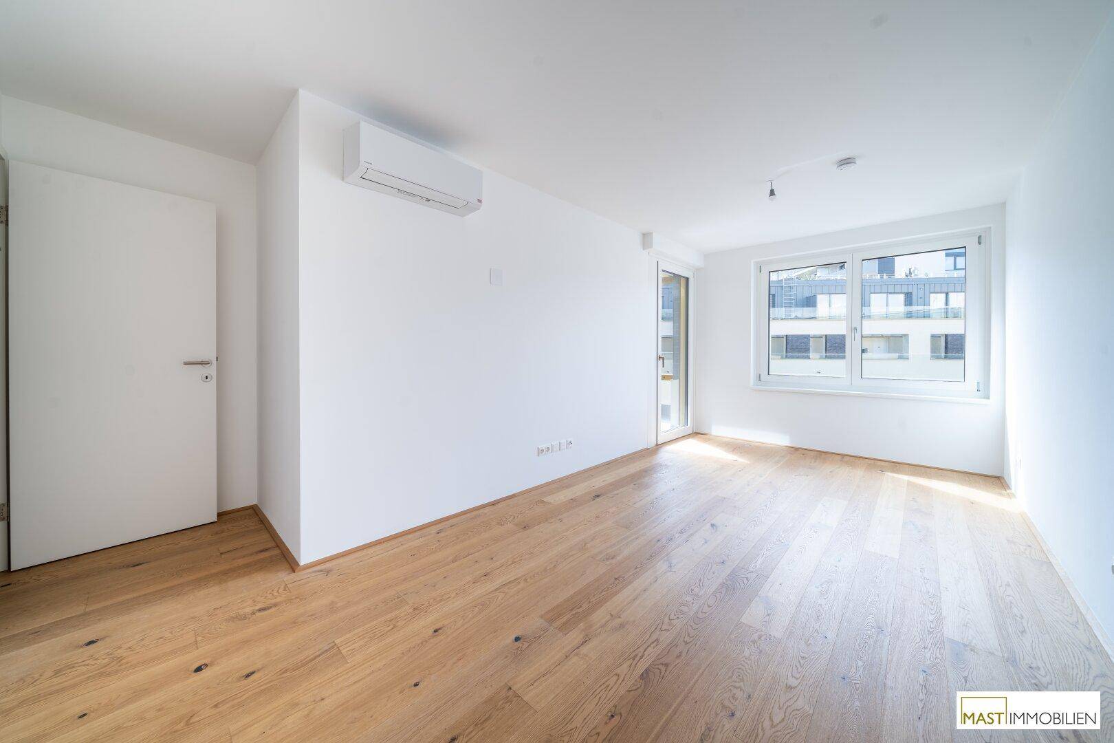 Modernes Schlafzimmer mit Holzboden, Klimaanlage und Fenster für natürliche Belichtung.