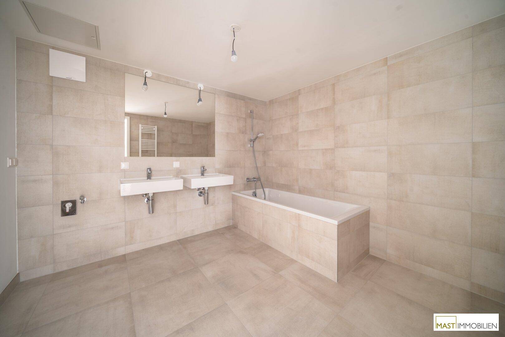 Modernes Badezimmer mit beigefarbenen Fliesen, Doppelwaschbecken und Badewanne.
