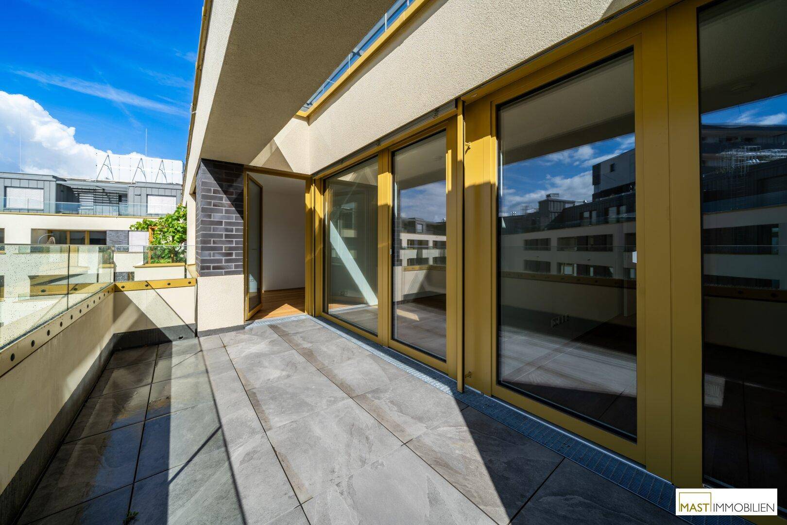 Heller Balkon mit Fliesenboden und großen Fenstern, die viel Licht in den Innenraum lassen.