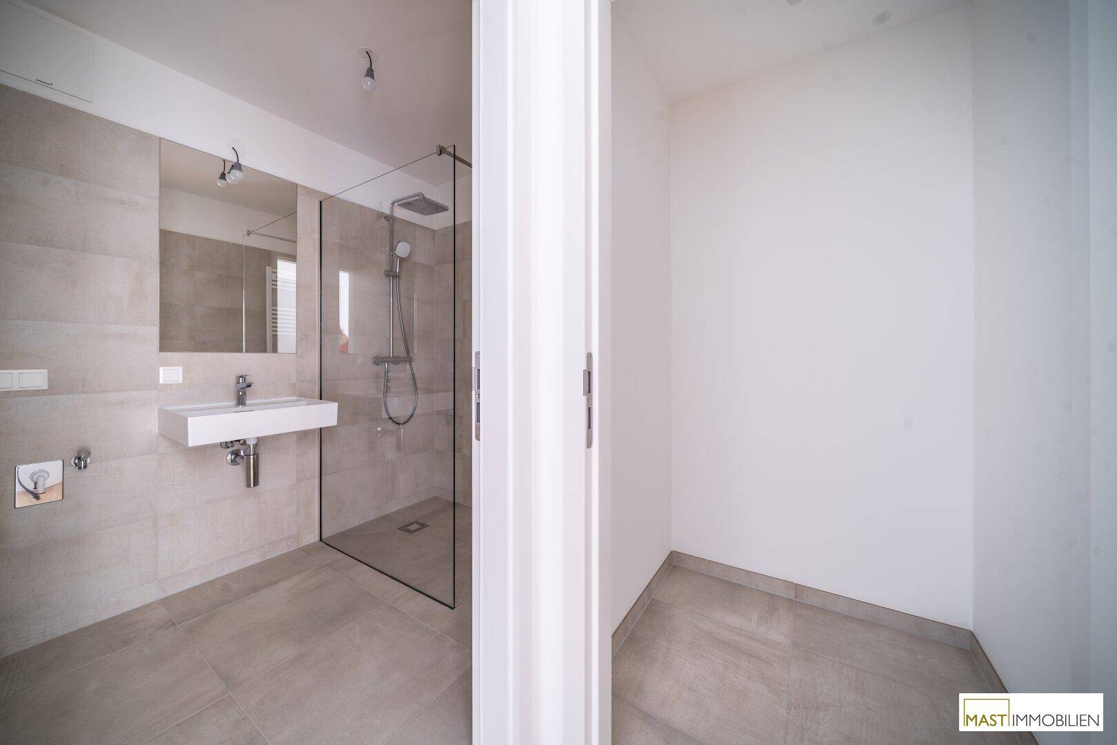 Modernes Badezimmer mit begehbarer Dusche, elegantem Waschbecken und großem Spiegel.