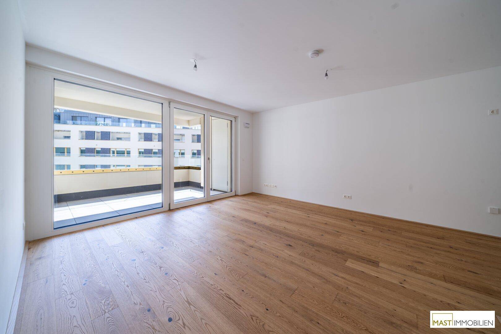 Geräumiges, helles Zimmer mit Parkettboden und Zugang zu einem sonnigen Balkon.