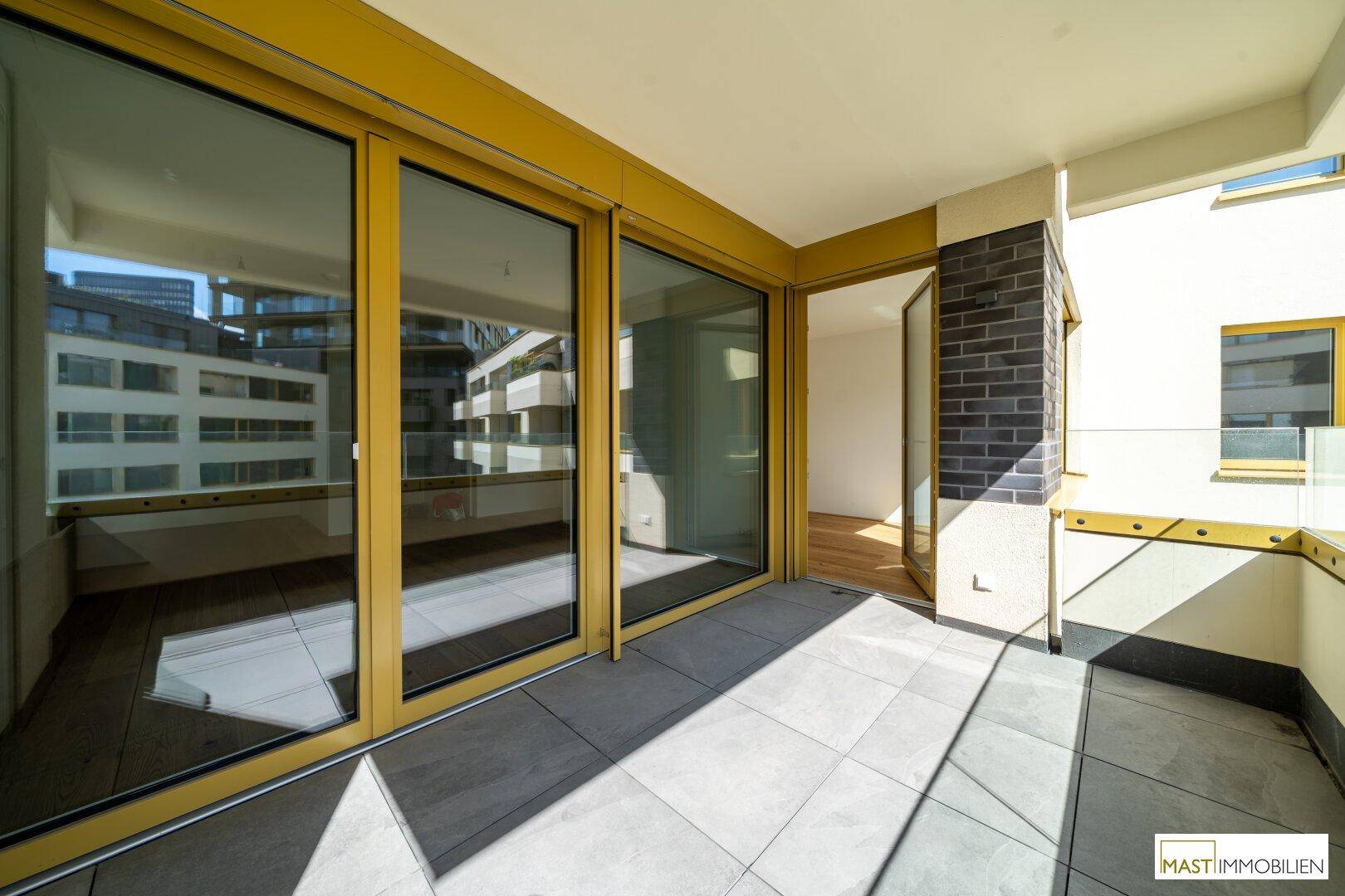 Heller Balkon mit großen Glasfronten und Zugang zu den Innenräumen.