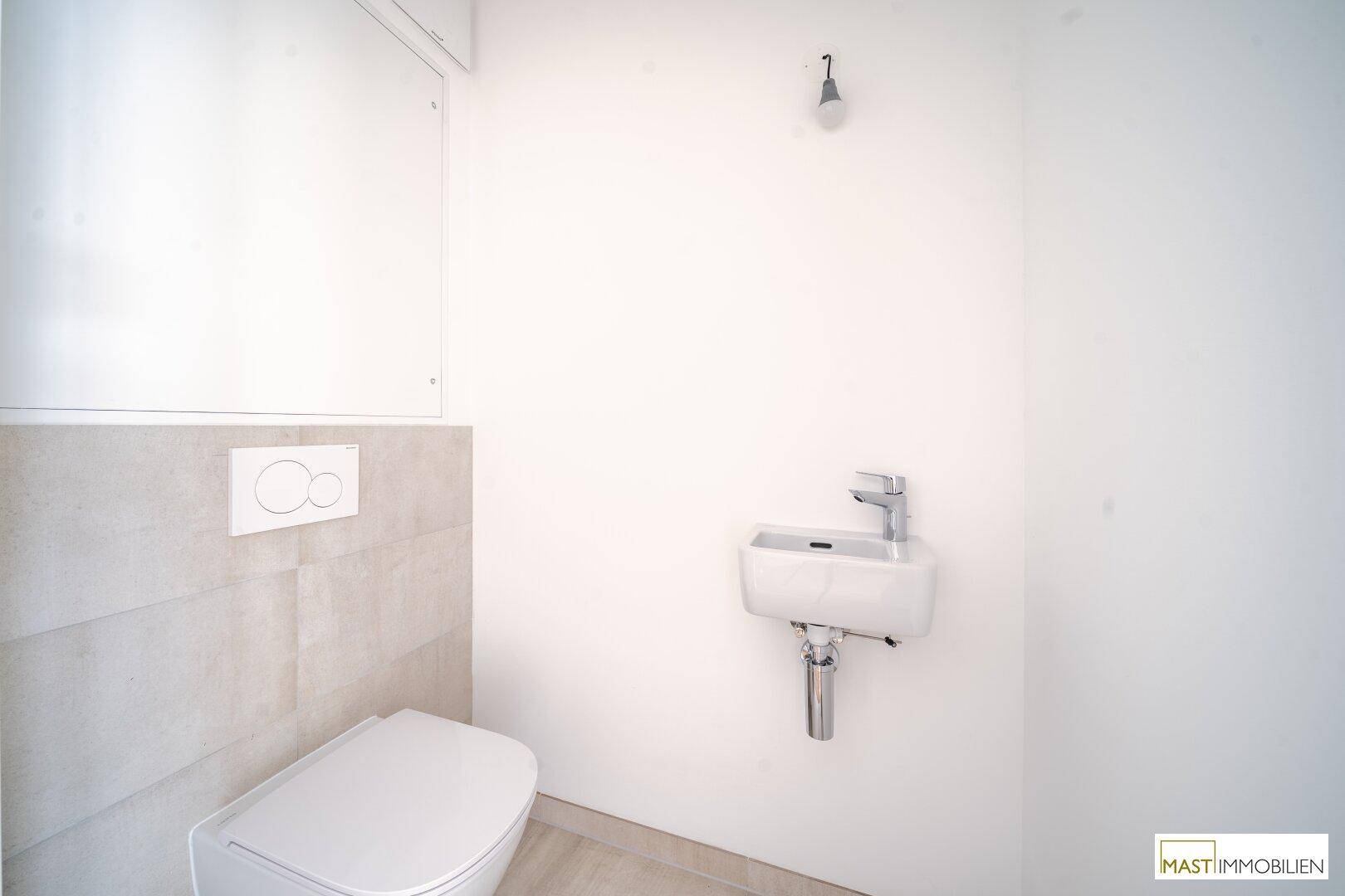 Separates Gäste-WC mit wandhängender Toilette und kleinem Waschbecken.