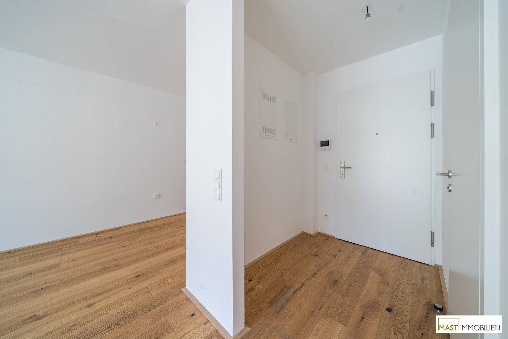 Heller Eingangsbereich mit Holzboden und weißer Eingangstür.
