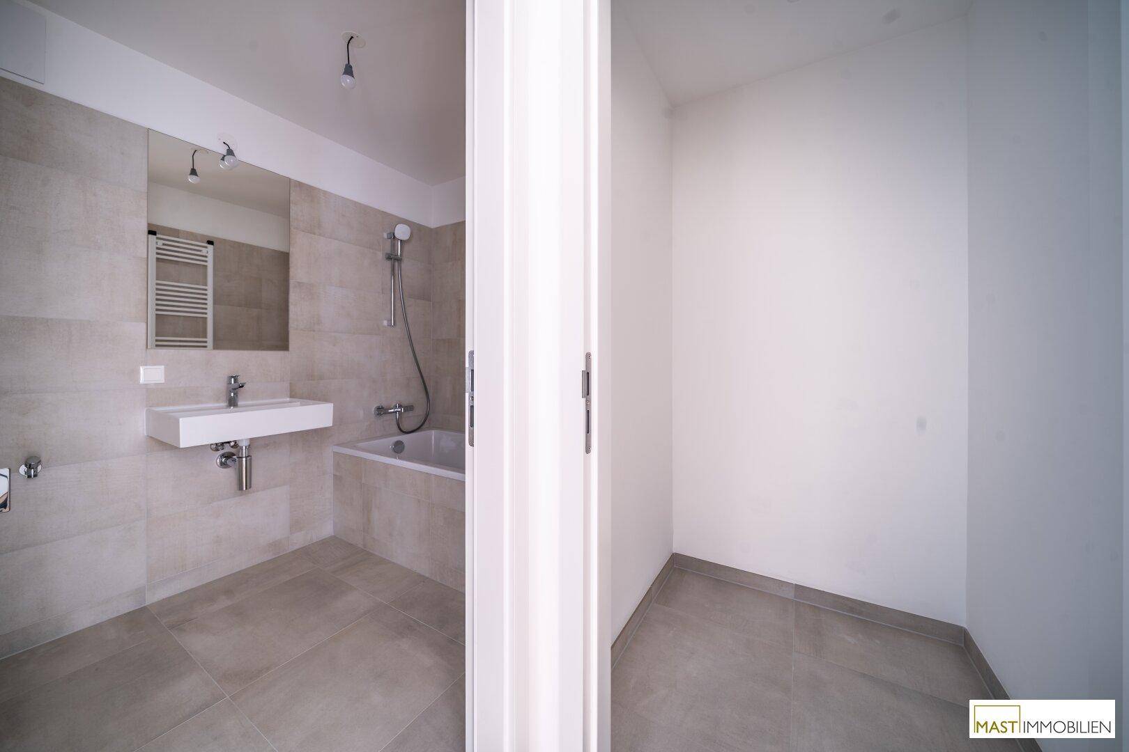 Modernes Badezimmer mit Badewanne, Waschbecken und hellen Fliesen.