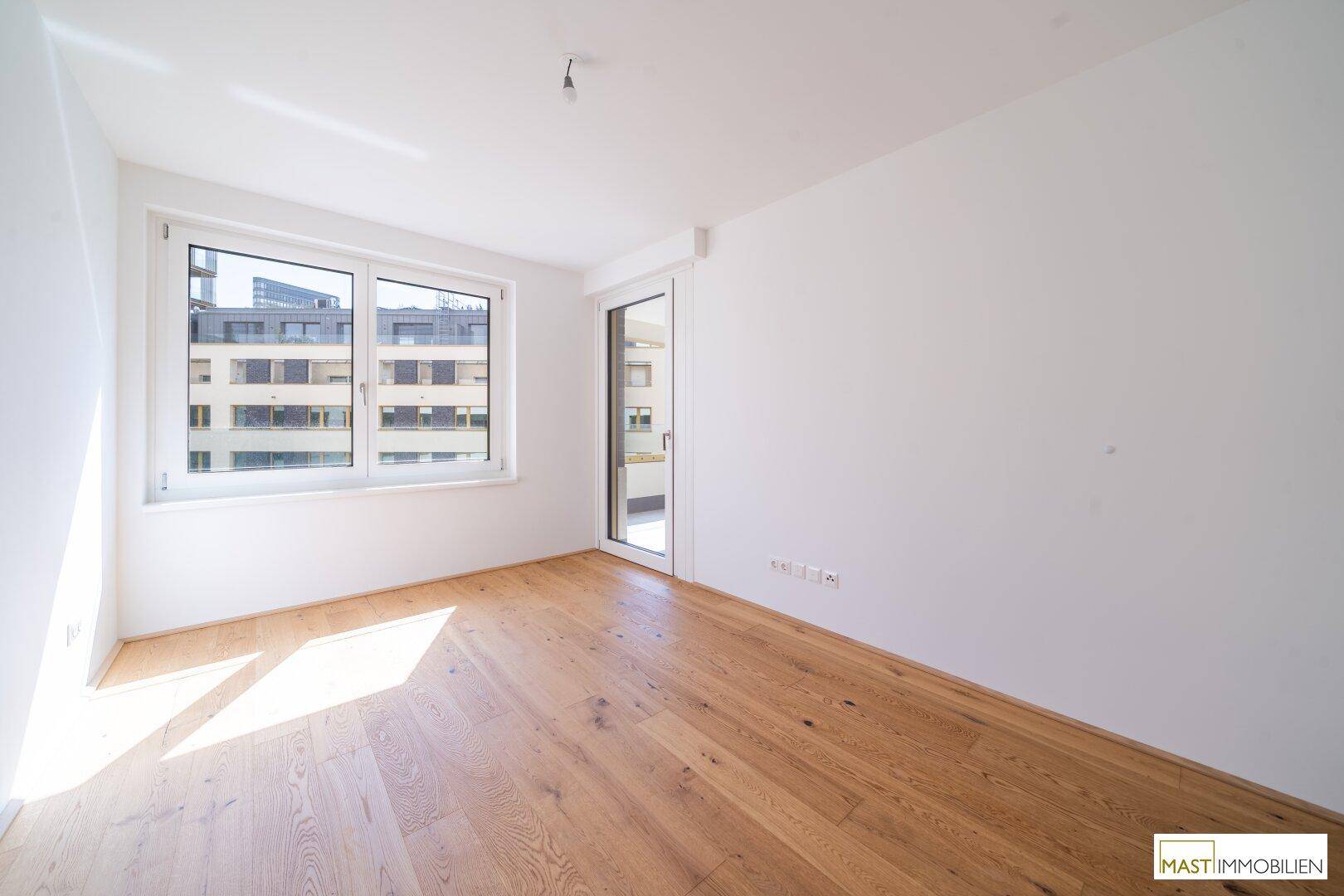 Helles Schlafzimmer mit Holzboden und Fenster mit Blick auf die Stadt.