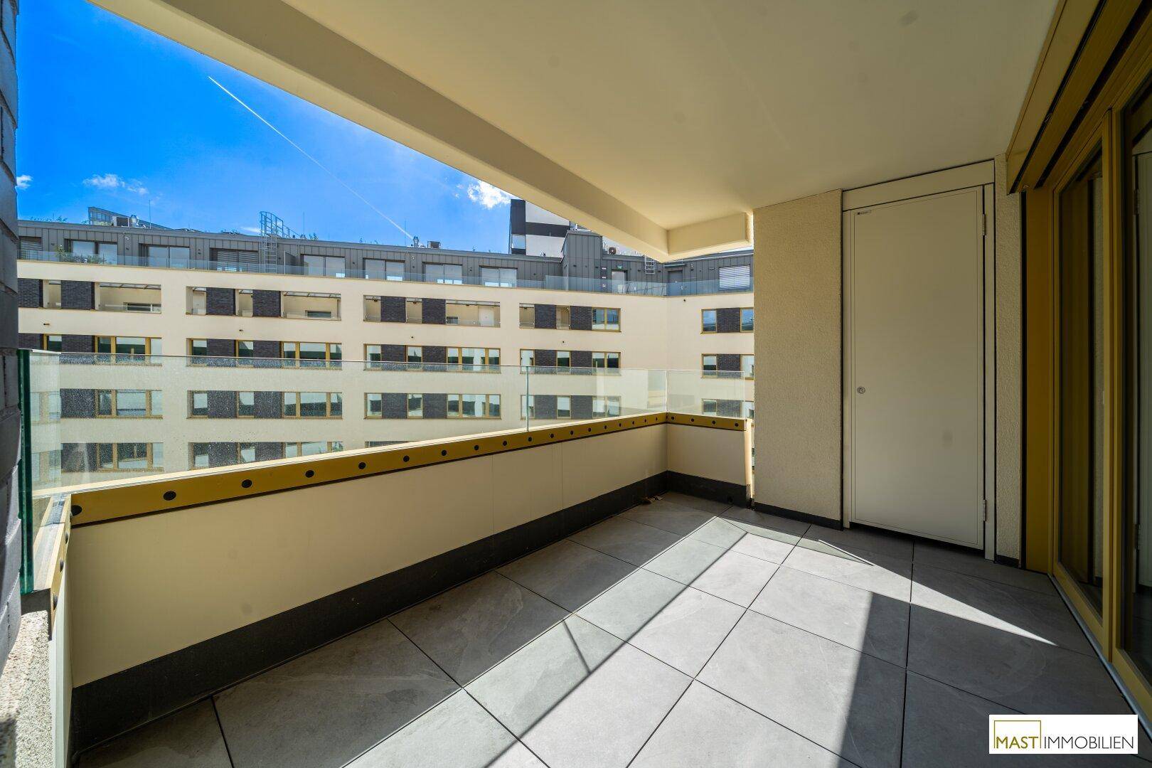 Geräumiger Balkon mit Fliesenboden und Glasbrüstung, bietet einen weiten Blick.