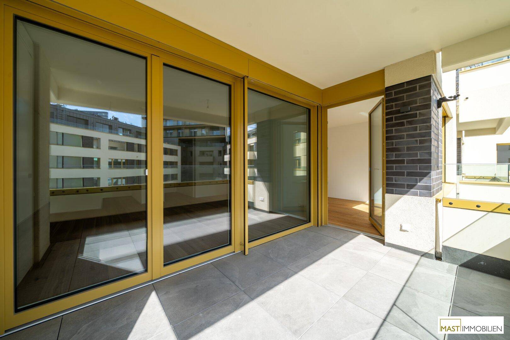 Heller Balkon mit Fliesenboden und Zugang zu den Innenräumen durch große Schiebetüren.
