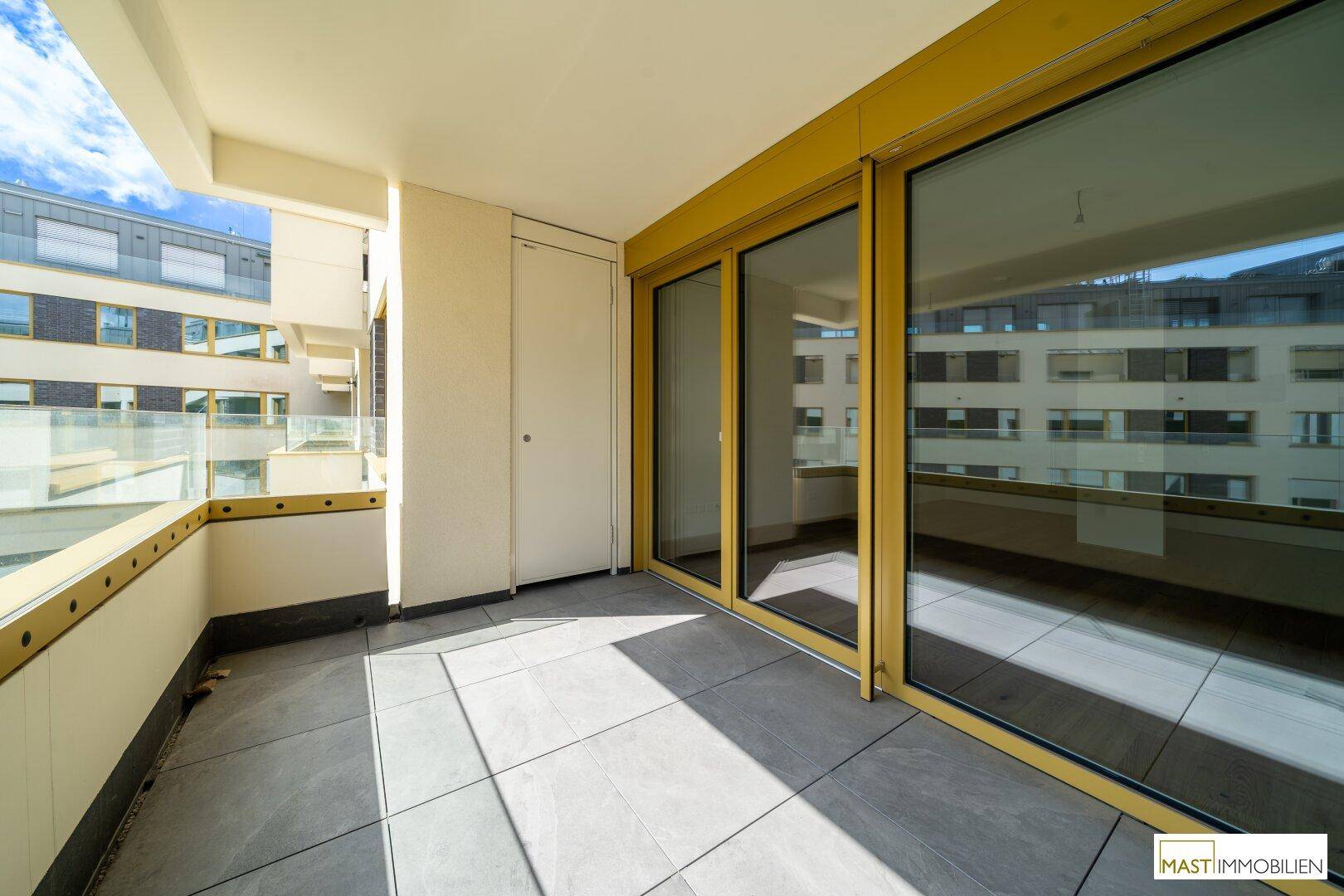 Geräumiger Balkon mit Fliesenboden und großen Schiebetüren zu den Innenräumen.