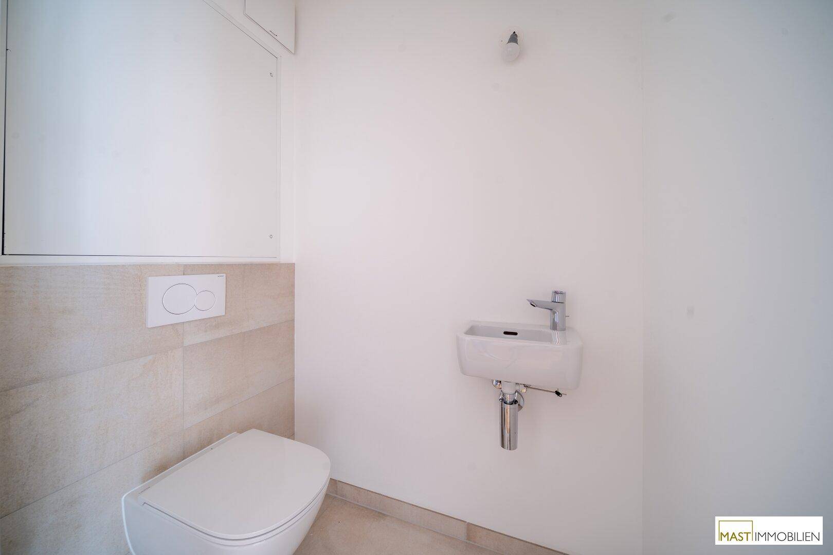 Separates Gäste-WC mit wandhängender Toilette und kleinem Handwaschbecken, in modernem Design.