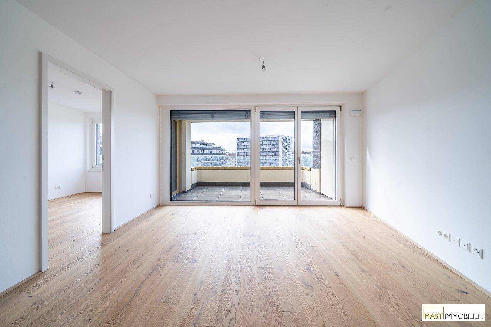 Lichtdurchfluteter Wohnbereich mit Parkett und Schiebetüren zum Balkon.