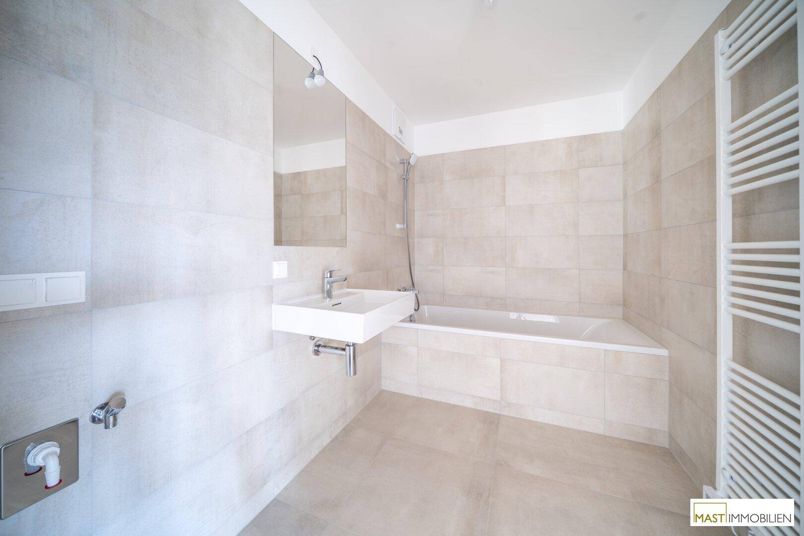 Modernes Badezimmer mit Badewanne, Waschbecken und beheiztem Handtuchhalter.
