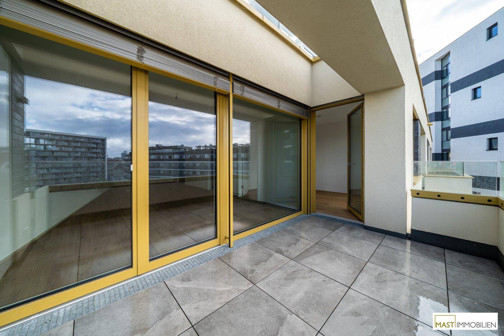 Heller Balkon mit großen Schiebetüren und Blick auf die Stadt.
