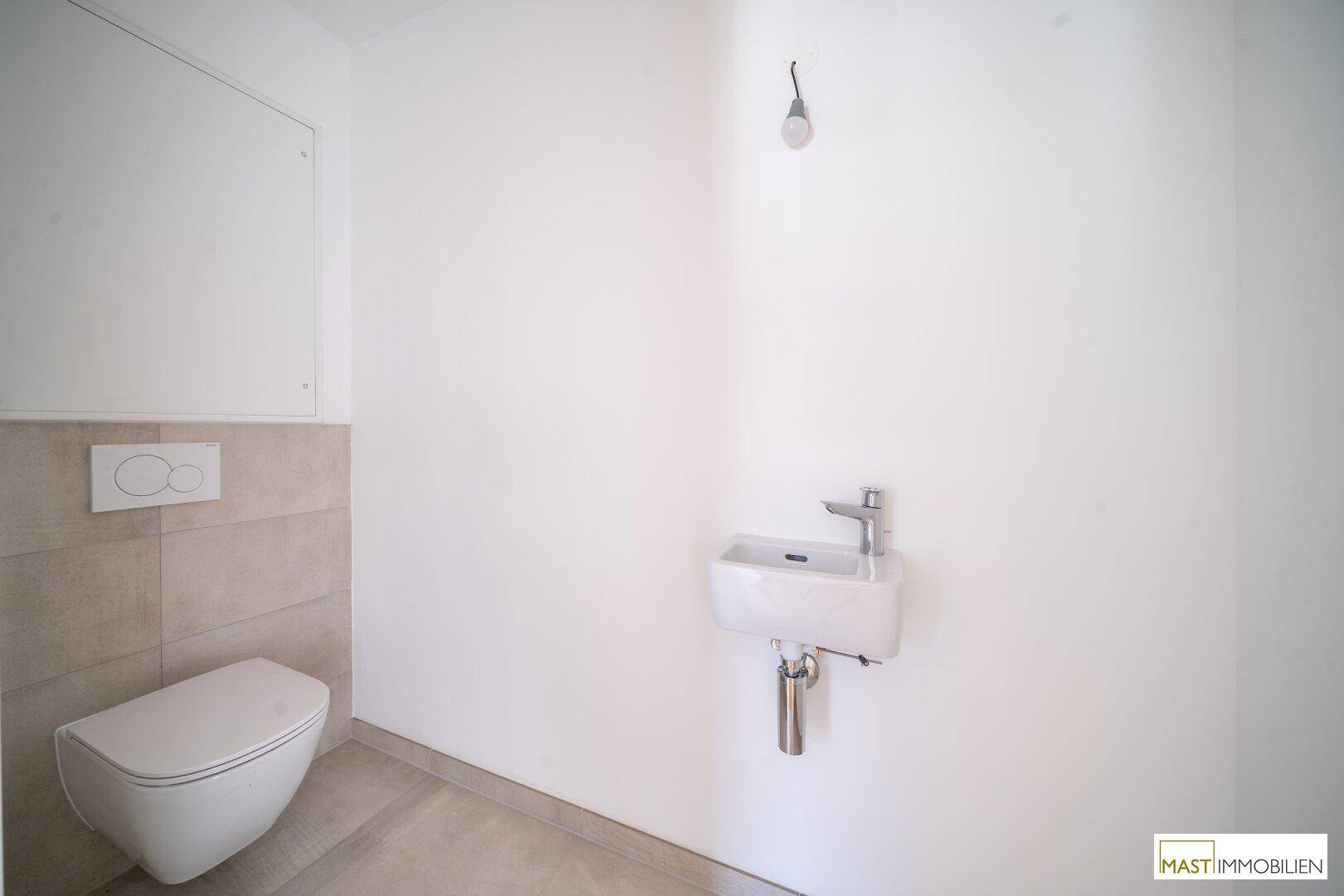 Funktionelles Gäste-WC mit wandhängender Toilette und kleinem Waschbecken, in neutralen Farbtönen gehalten.