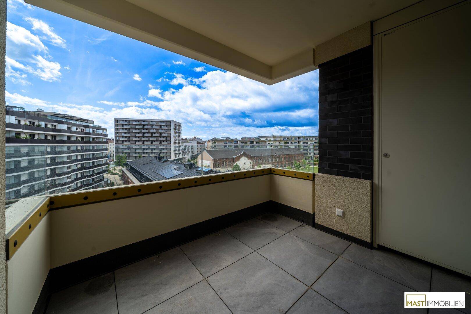 Geräumiger Balkon mit Fliesenboden und weitem Blick auf die umliegende Stadtbebauung.