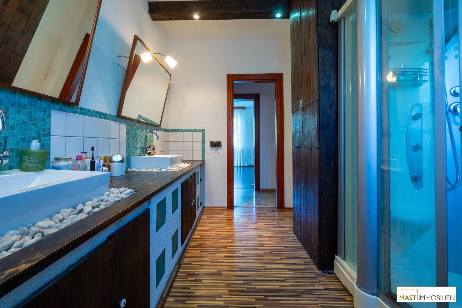 Badezimmer mit Duschkabine, Doppelwaschbecken und rustikalen Holzelementen.