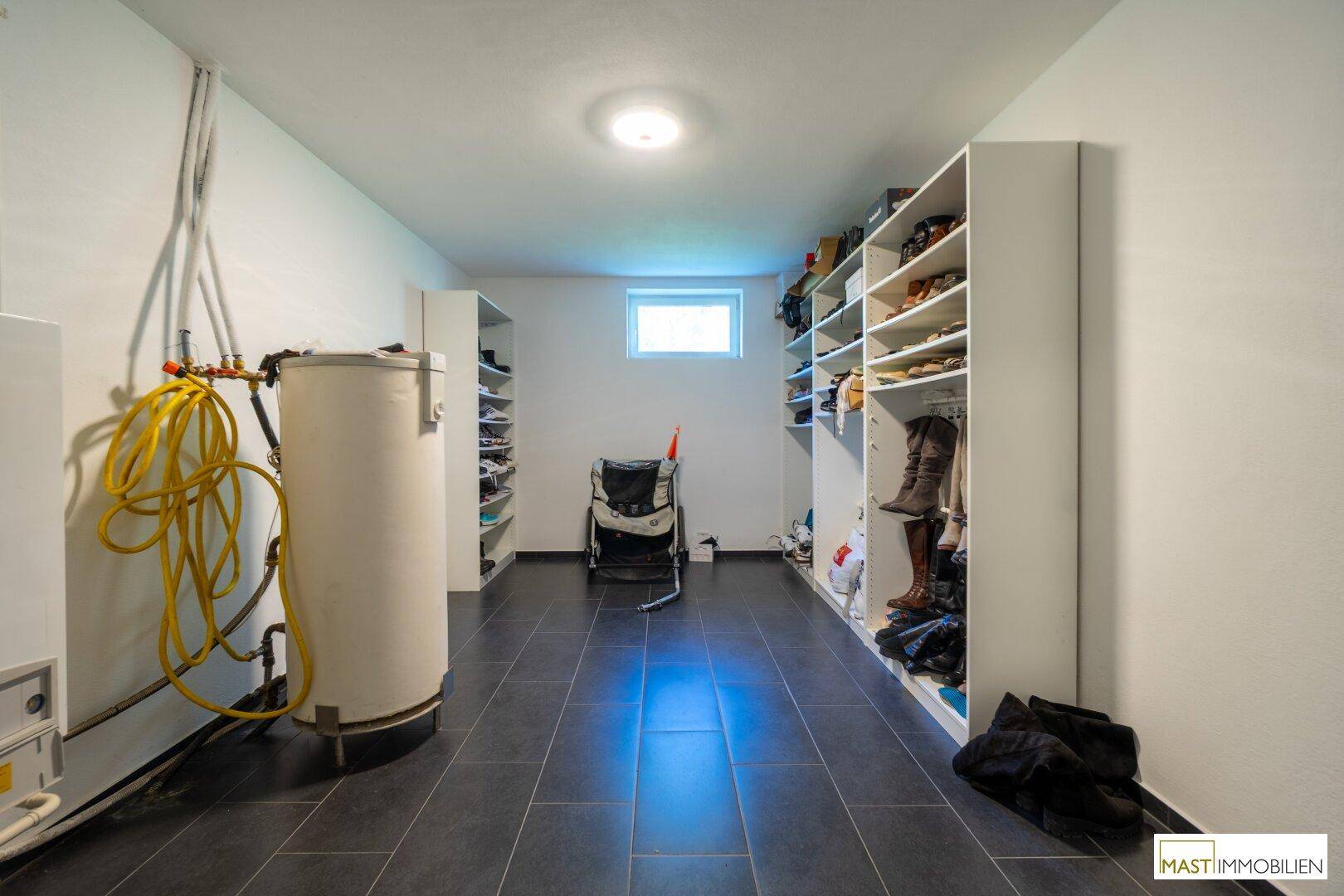Funktionaler Hauswirtschaftsraum mit Boiler, Fliesenboden und Regalen für zusätzlichen Stauraum.