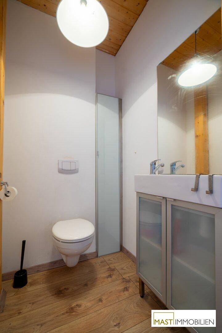 Modernes Gäste-WC mit Holzdecke, schwebendem Waschbecken und Wand-WC.