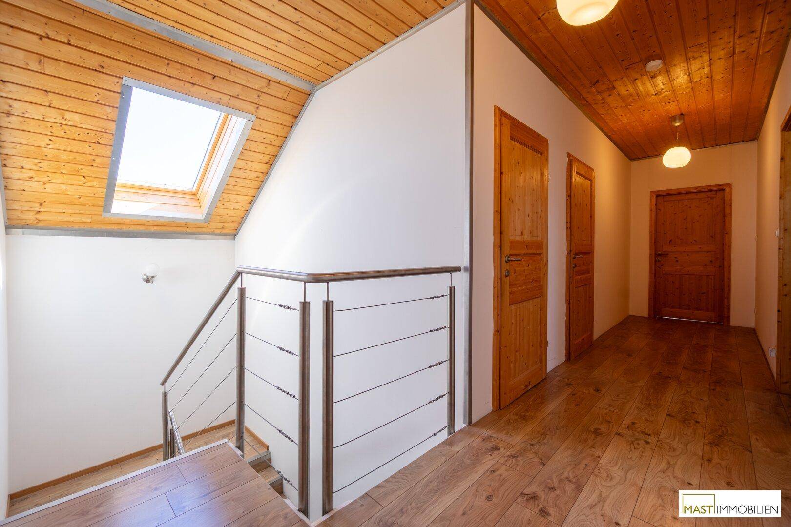 Heller Flur im Dachgeschoss mit Holzdecke, Holzboden und Treppenaufgang.