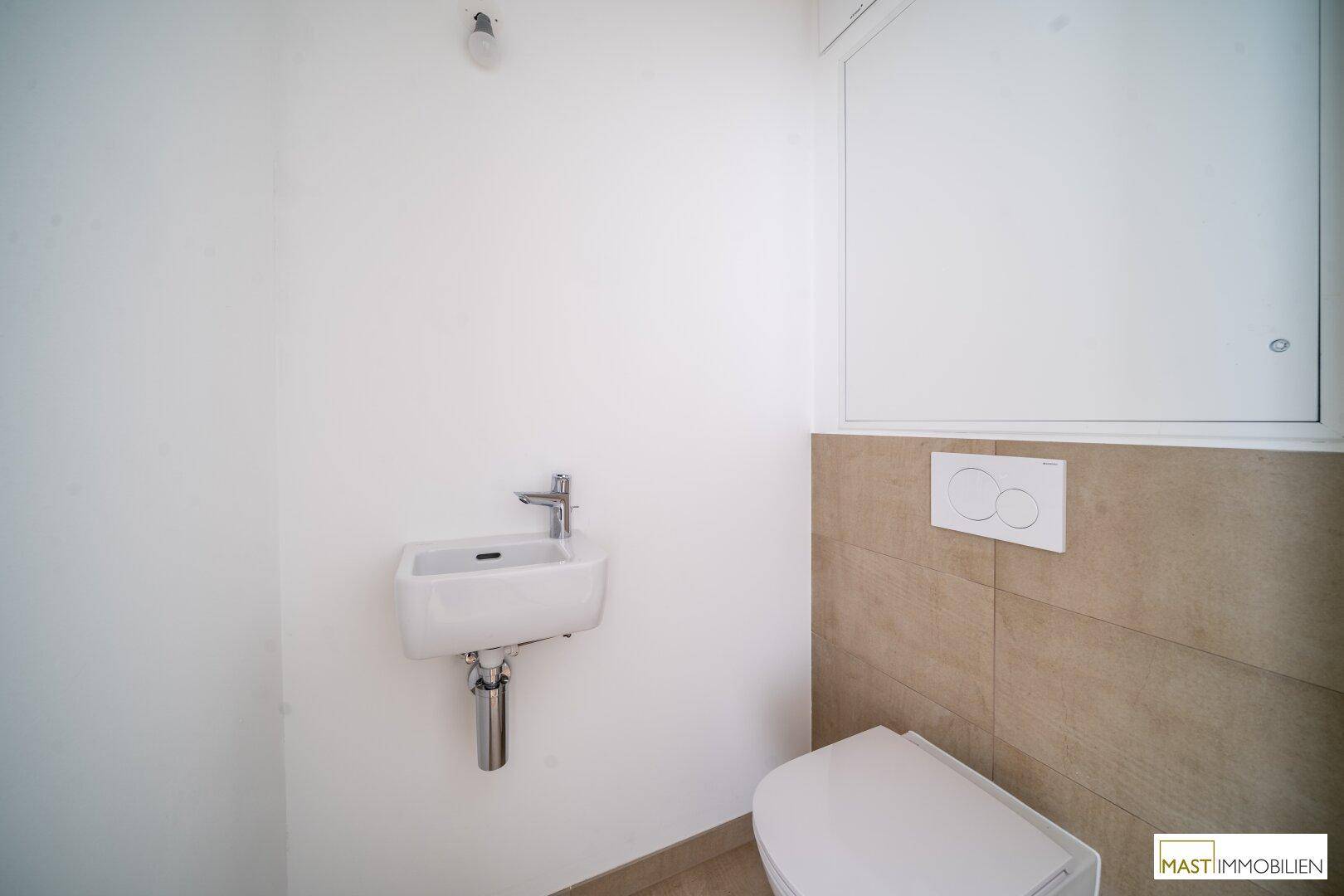 Modernes Gäste-WC mit Wand-WC und kleinem Waschbecken, halbhoch gefliest.